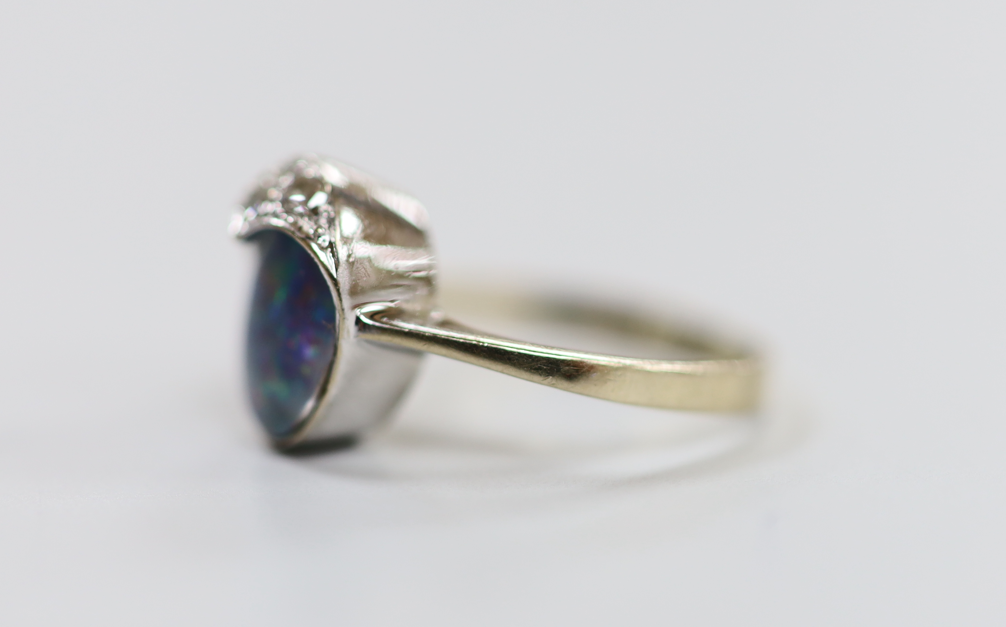 An 18ct white gold, black opal doublet and three stone diamond set ring, size F, gross weight 3 grams.